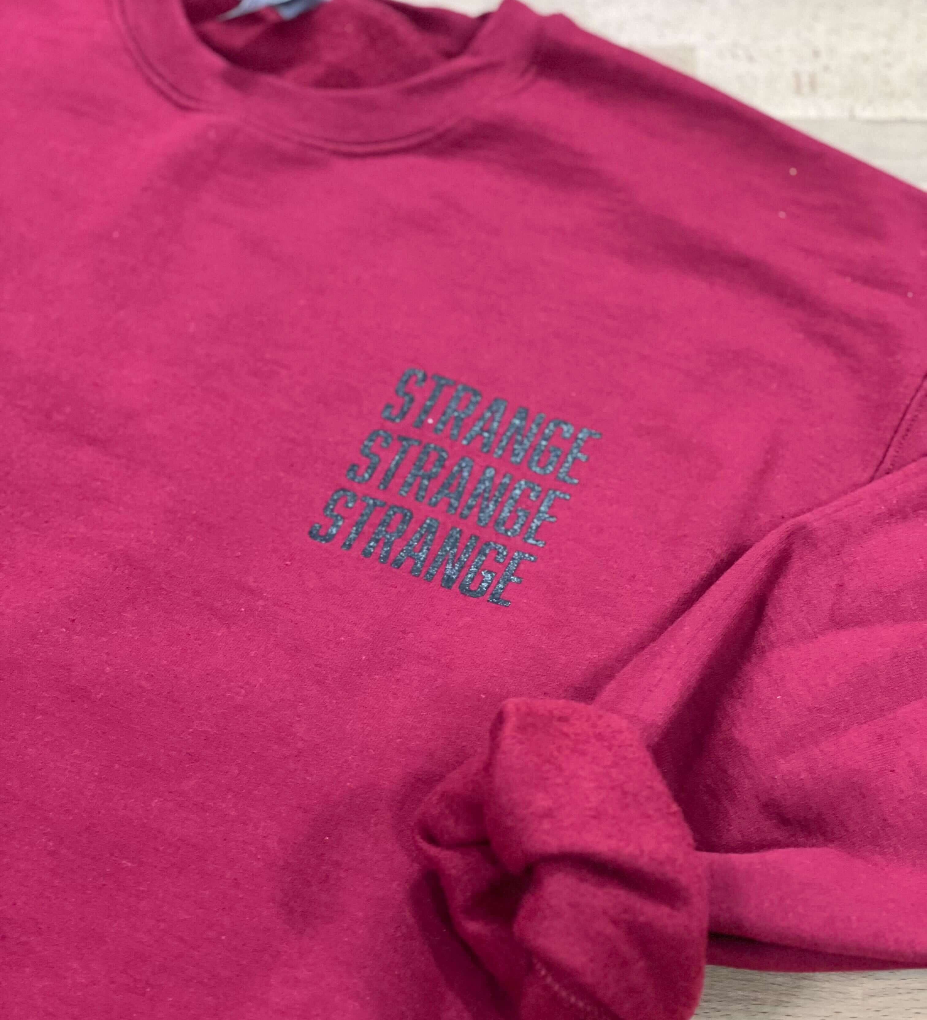 "Strange Strange Strange" small logo crewnecks